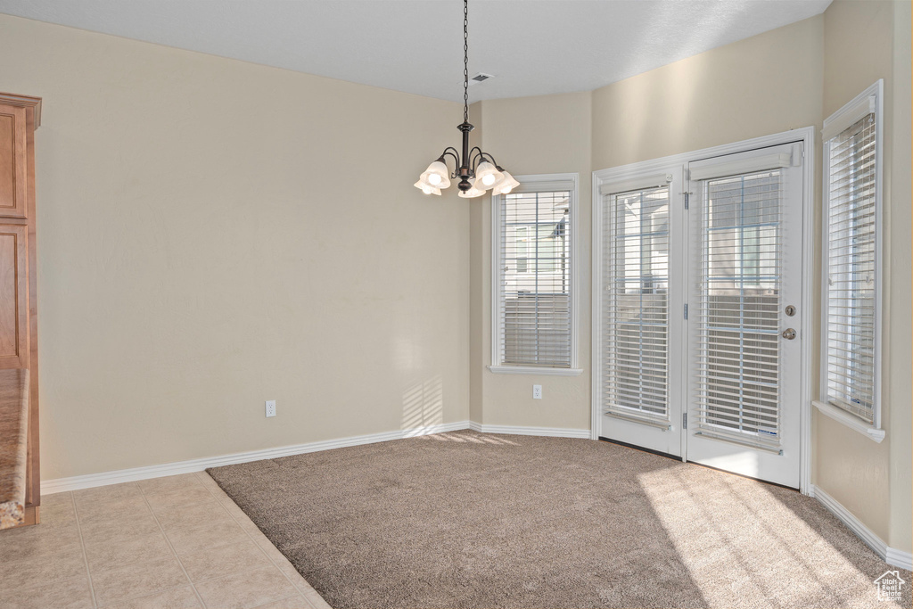 Tiled spare room featuring an inviting chandelier