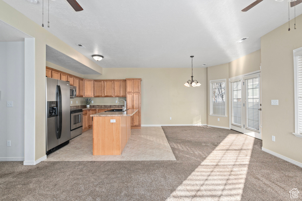 Kitchen with sink, decorative light fixtures, a center island with sink, light colored carpet, and stainless steel appliances