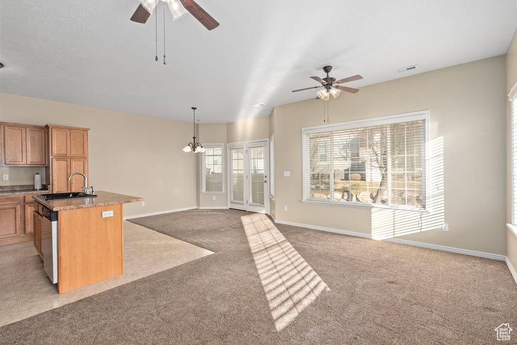 Kitchen featuring pendant lighting, sink, light colored carpet, a center island with sink, and stainless steel dishwasher