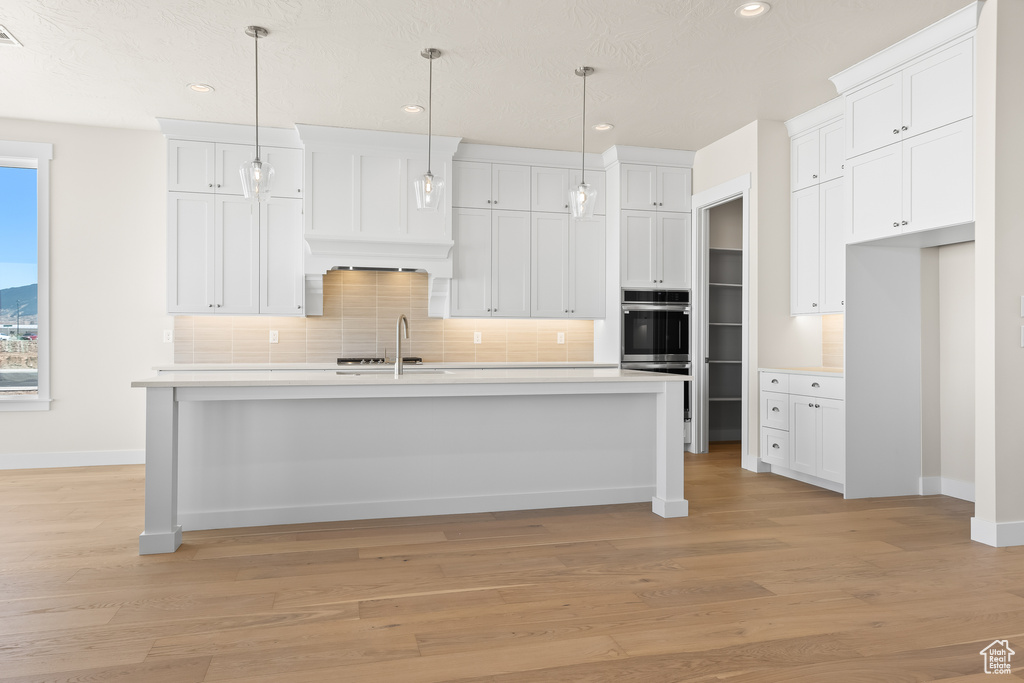 Kitchen featuring an island with sink, sink, and white cabinets