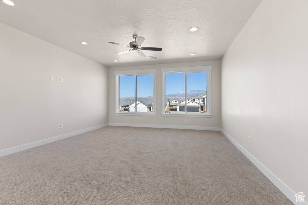 Carpeted spare room with ceiling fan and a textured ceiling