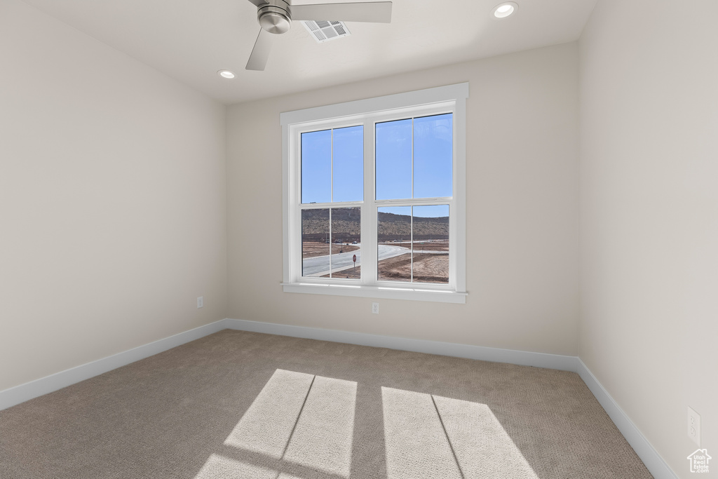 Carpeted empty room featuring ceiling fan