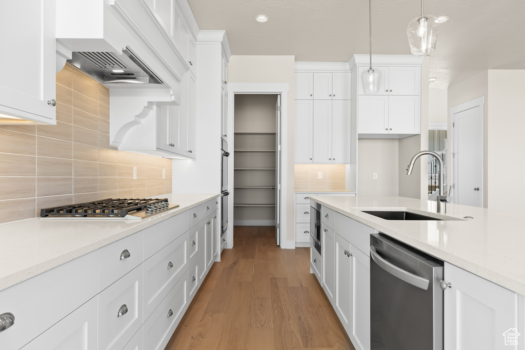 Kitchen featuring white cabinetry, appliances with stainless steel finishes, sink, and pendant lighting