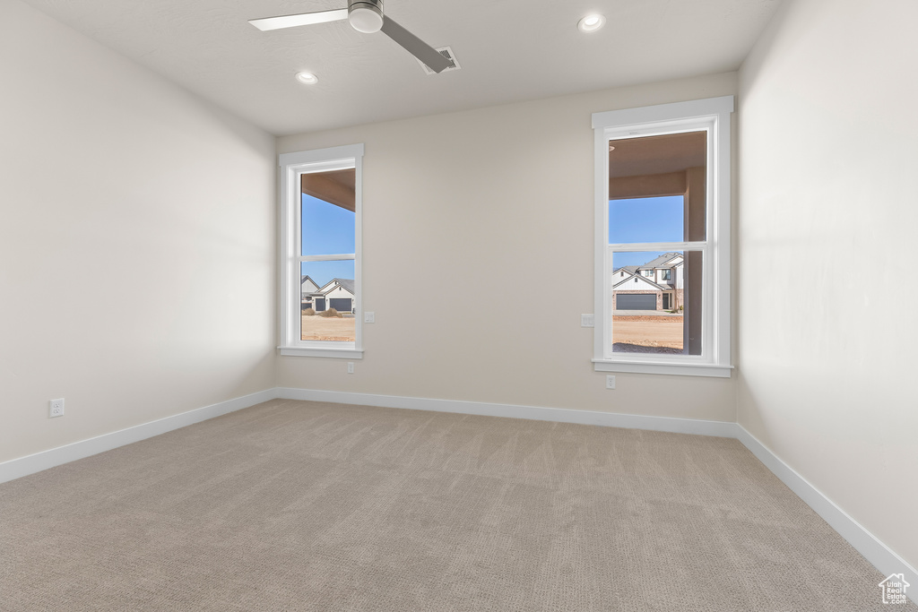 Empty room with ceiling fan and light carpet