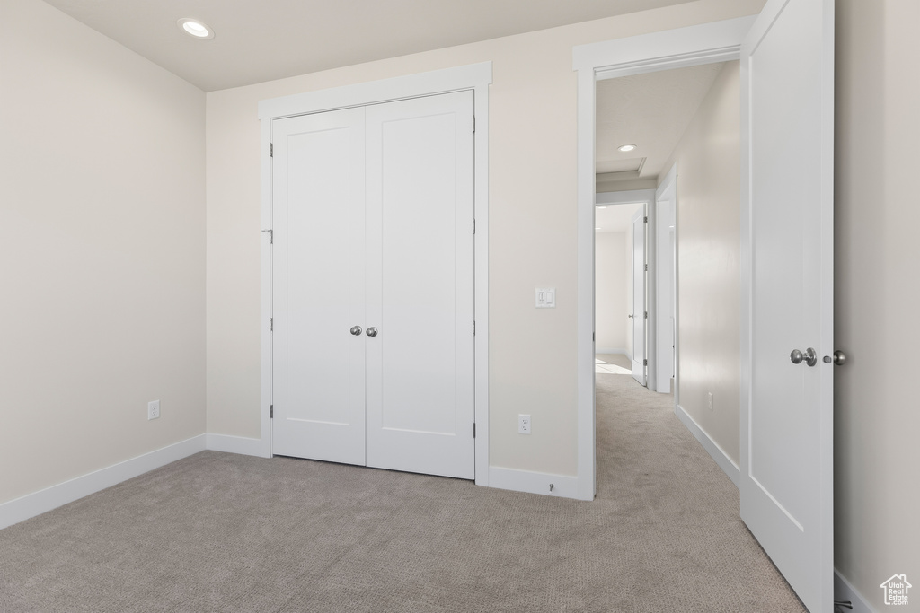 Unfurnished bedroom featuring light carpet and a closet