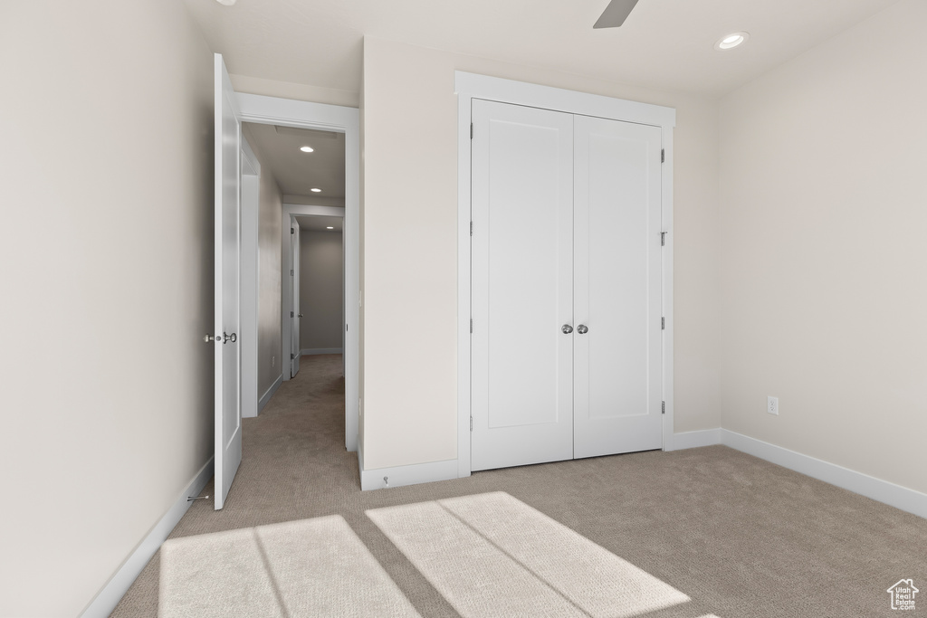 Unfurnished bedroom with light carpet, a closet, and ceiling fan