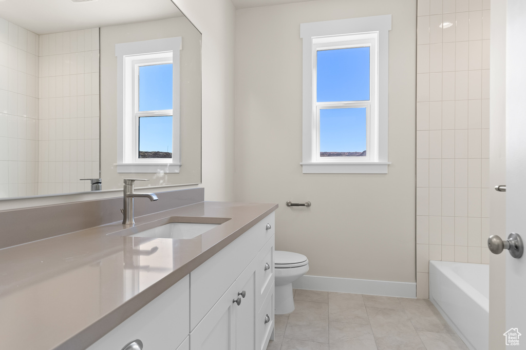 Full bathroom featuring tile patterned flooring, vanity, tiled shower / bath combo, and toilet