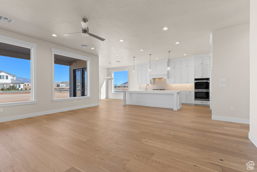 Unfurnished living room featuring ceiling fan, sink, and light hardwood / wood-style flooring