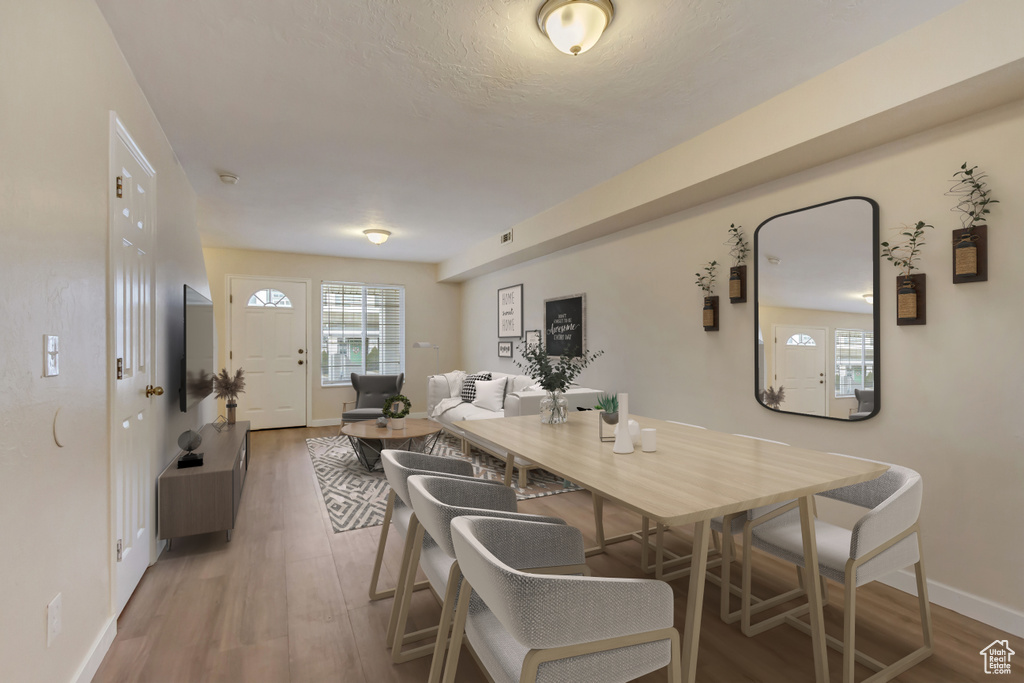 Dining room with light wood-style floors, visible vents, and baseboards