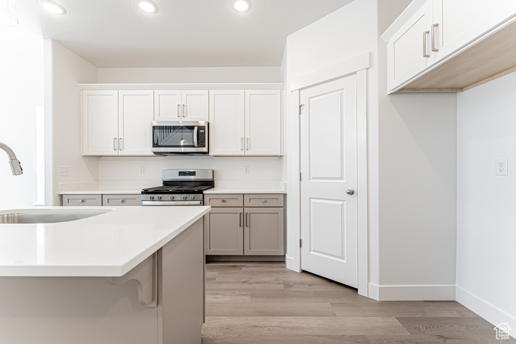 Kitchen featuring stainless steel appliances, a sink, light wood-style floors, recessed lighting, and light countertops