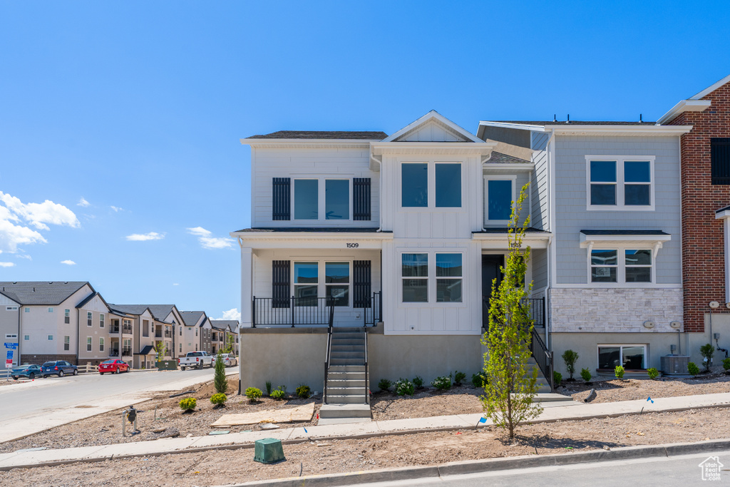 Multi unit property with board and batten siding, stairway, a residential view, and central air condition unit