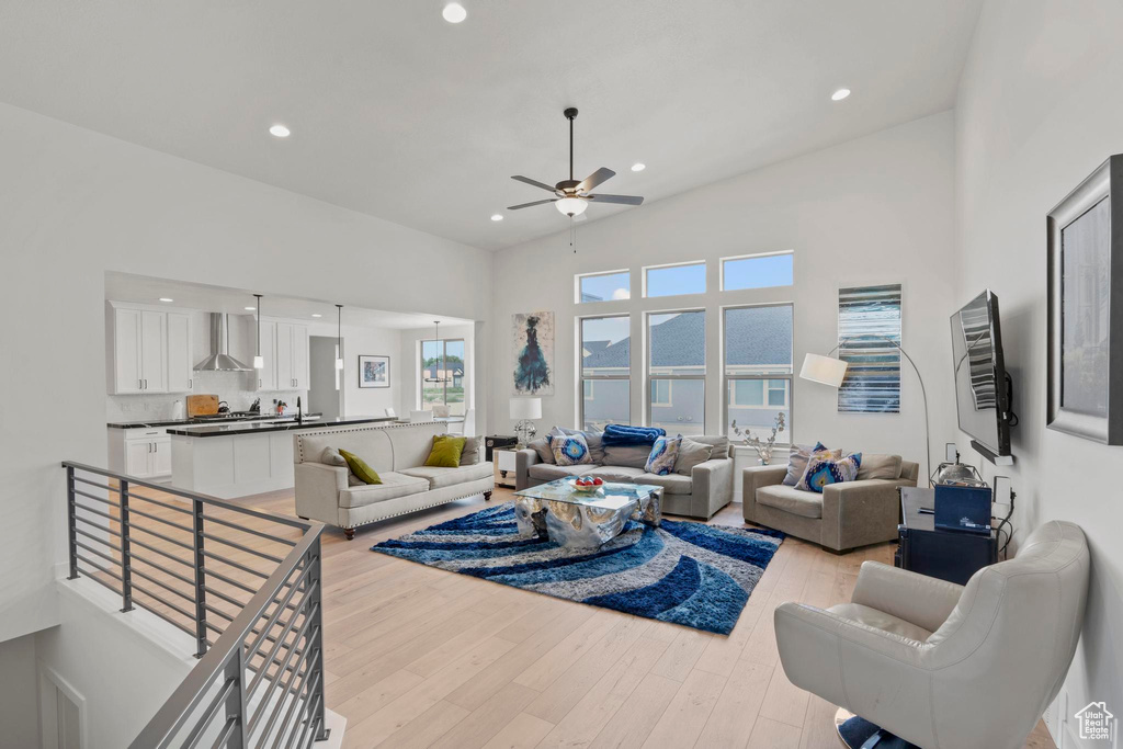 Living room with a high ceiling, ceiling fan, and light hardwood / wood-style flooring