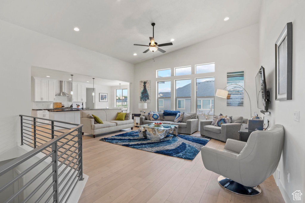 Living room with light hardwood / wood-style flooring, high vaulted ceiling, and ceiling fan