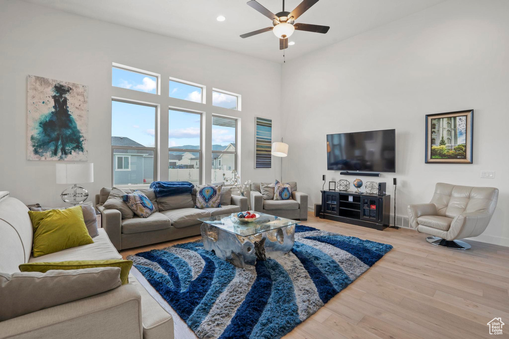 Living room featuring ceiling fan, hardwood / wood-style floors, and a towering ceiling