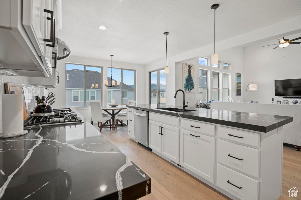 Kitchen with sink, appliances with stainless steel finishes, white cabinetry, an island with sink, and decorative light fixtures