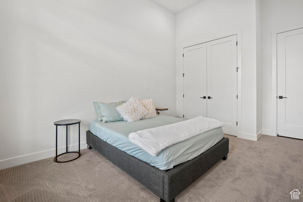 Bedroom with light colored carpet and a closet