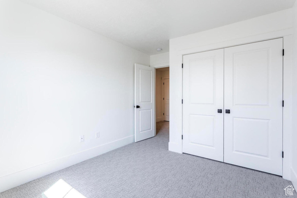 Unfurnished bedroom with light colored carpet and a closet