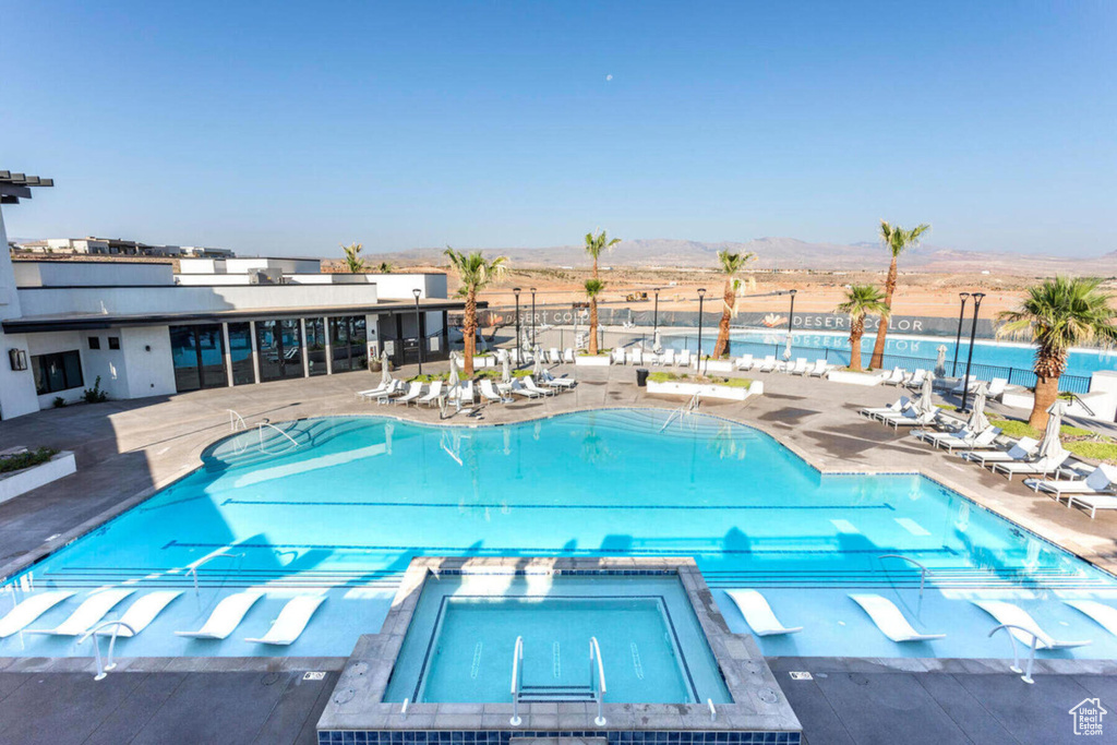 View of pool with a hot tub, a mountain view, and a patio area