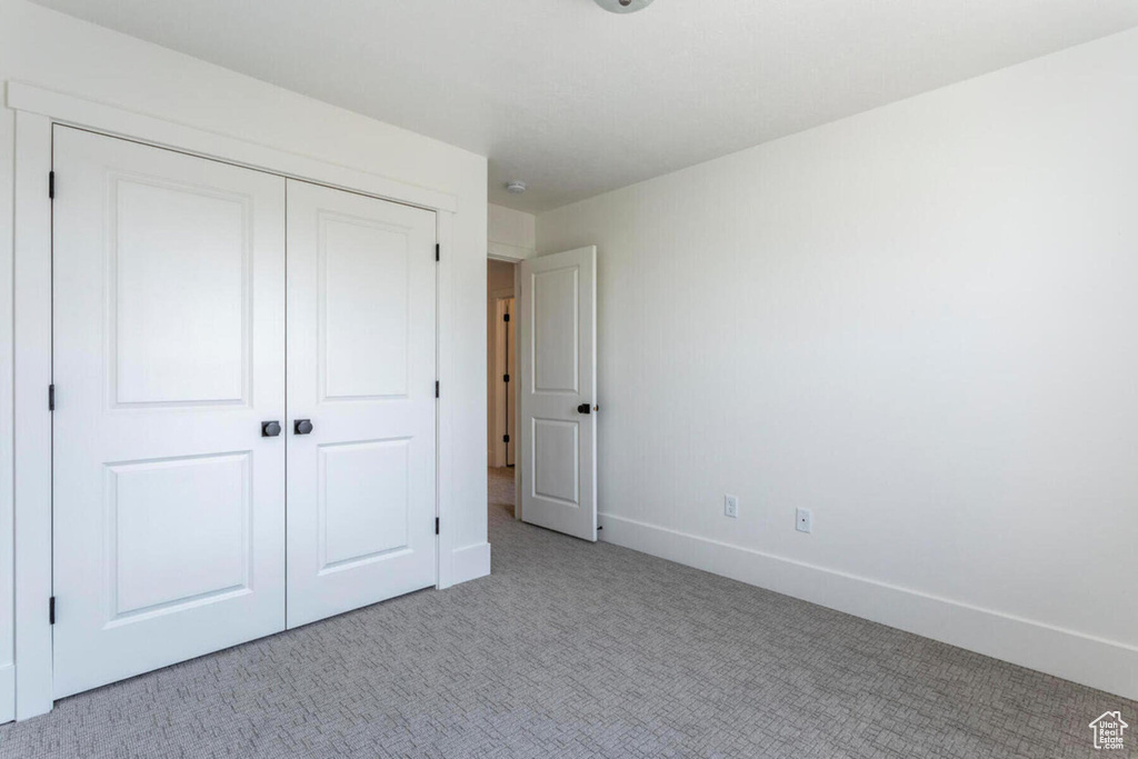 Unfurnished bedroom with light colored carpet and a closet