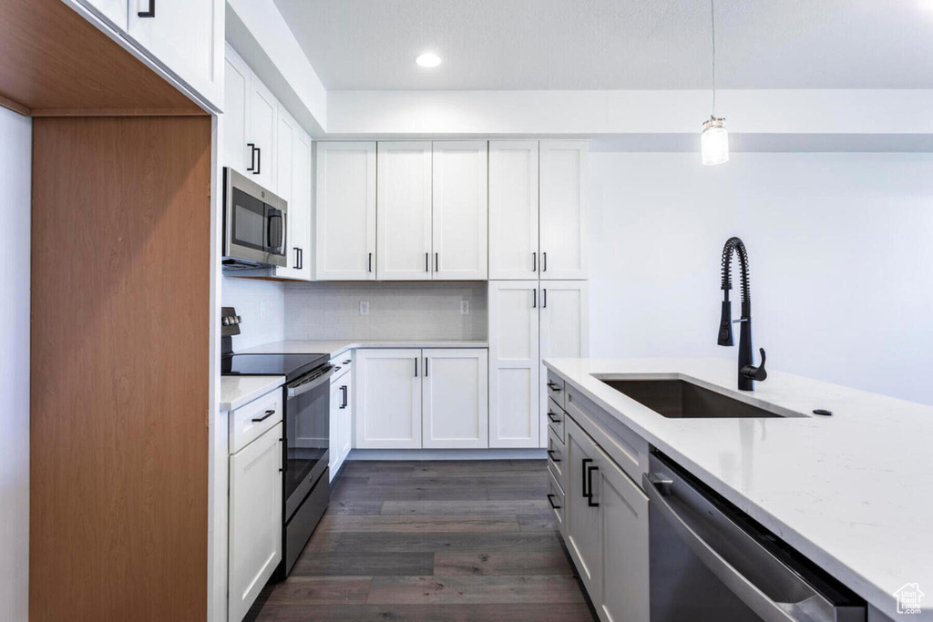 Kitchen featuring stainless steel appliances, white cabinetry, sink, and pendant lighting