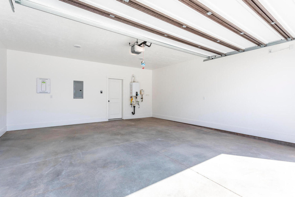 Garage with a garage door opener, electric panel, and tankless water heater