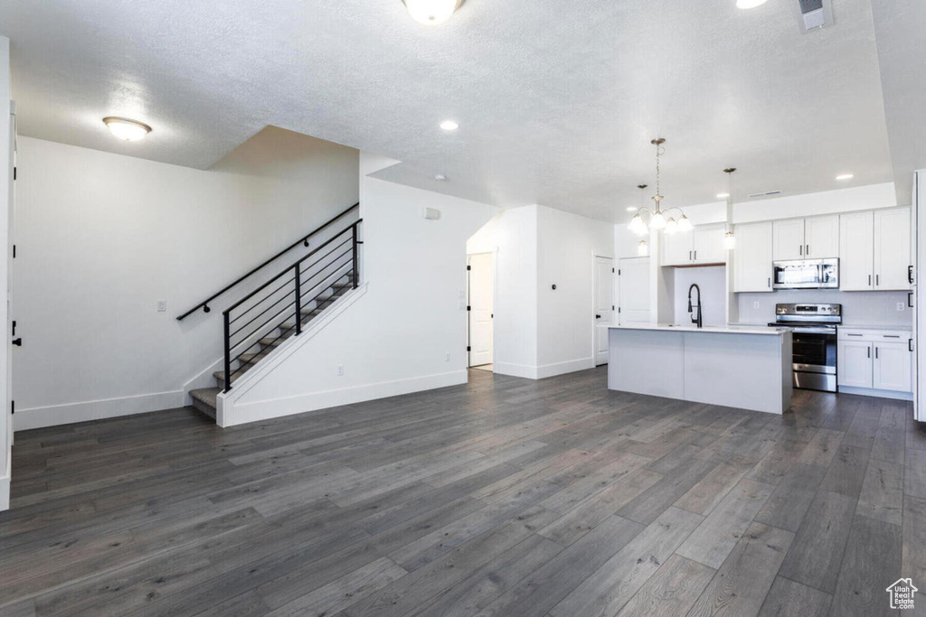 Kitchen featuring sink, a kitchen island with sink, hanging light fixtures, stainless steel appliances, and white cabinets