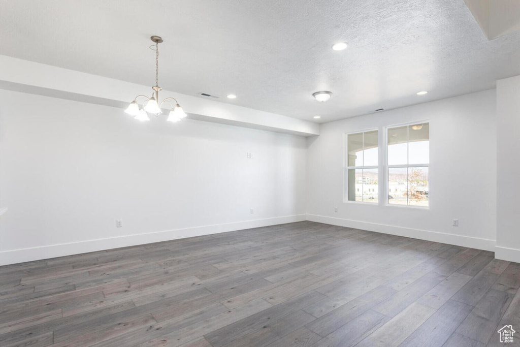 Unfurnished room featuring dark hardwood / wood-style floors, an inviting chandelier, and a textured ceiling