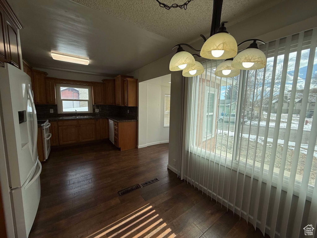 Kitchen featuring sink, tasteful backsplash, a textured ceiling, dark hardwood / wood-style floors, and white appliances