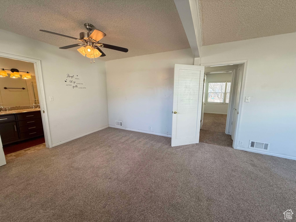 Unfurnished bedroom featuring light colored carpet, a textured ceiling, and ensuite bath