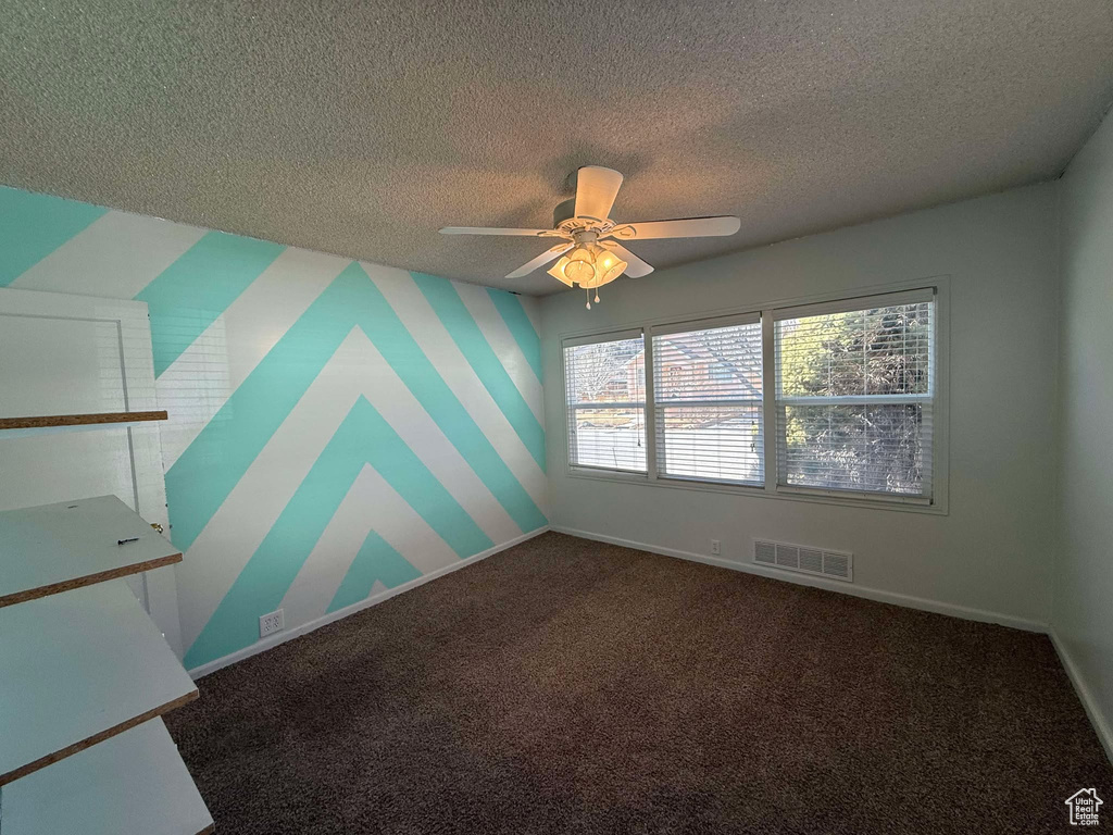 Spare room featuring ceiling fan, carpet flooring, and a textured ceiling