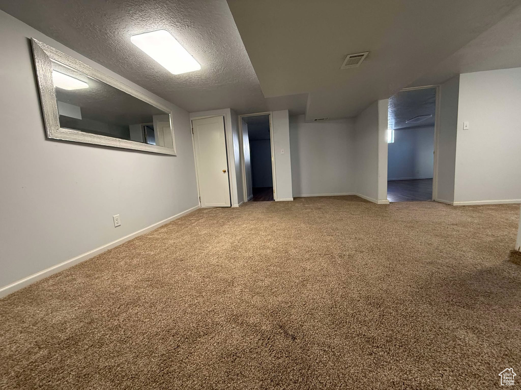 Basement featuring carpet flooring and a textured ceiling