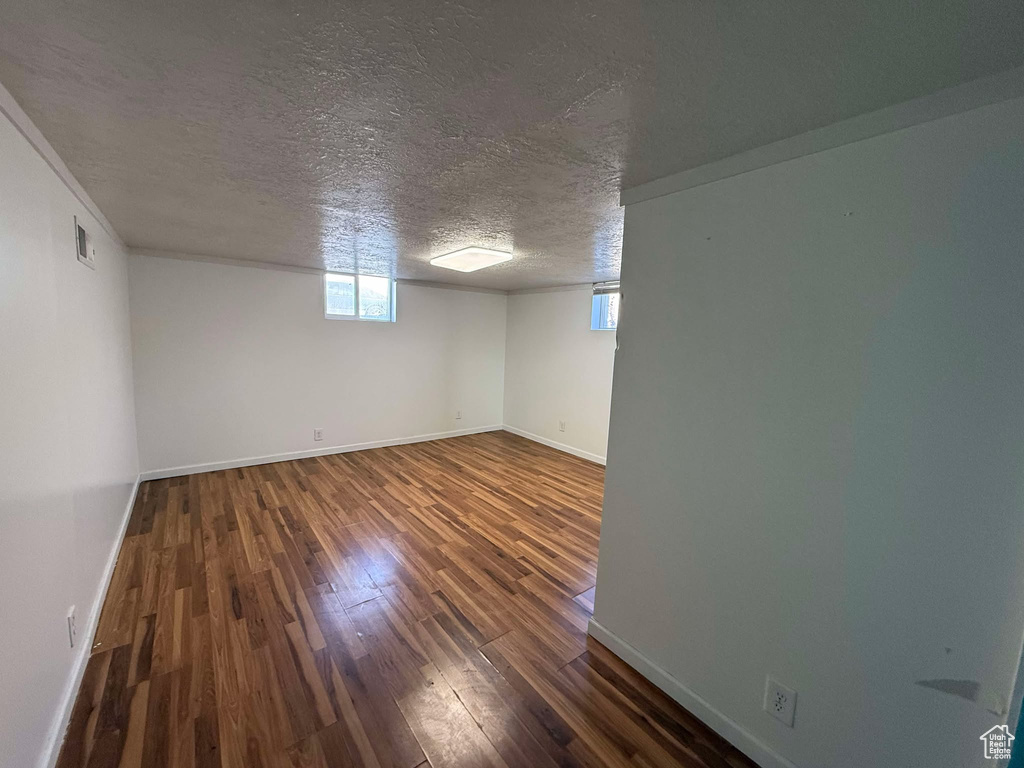 Basement with dark hardwood / wood-style flooring and a textured ceiling