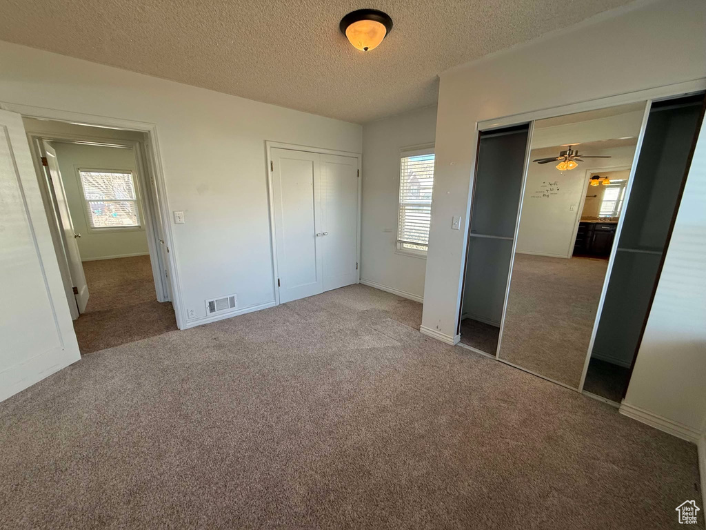 Unfurnished bedroom featuring multiple windows and carpet flooring