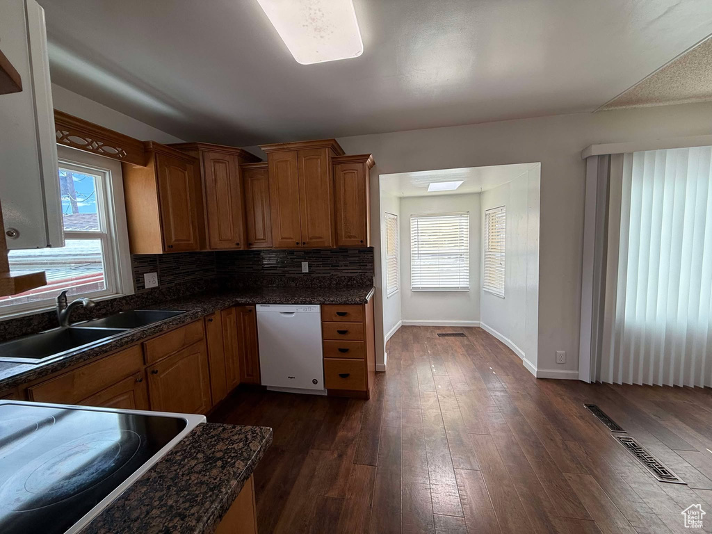 Kitchen with white dishwasher, sink, decorative backsplash, and dark hardwood / wood-style flooring