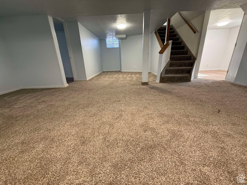 Basement with a textured ceiling and carpet flooring