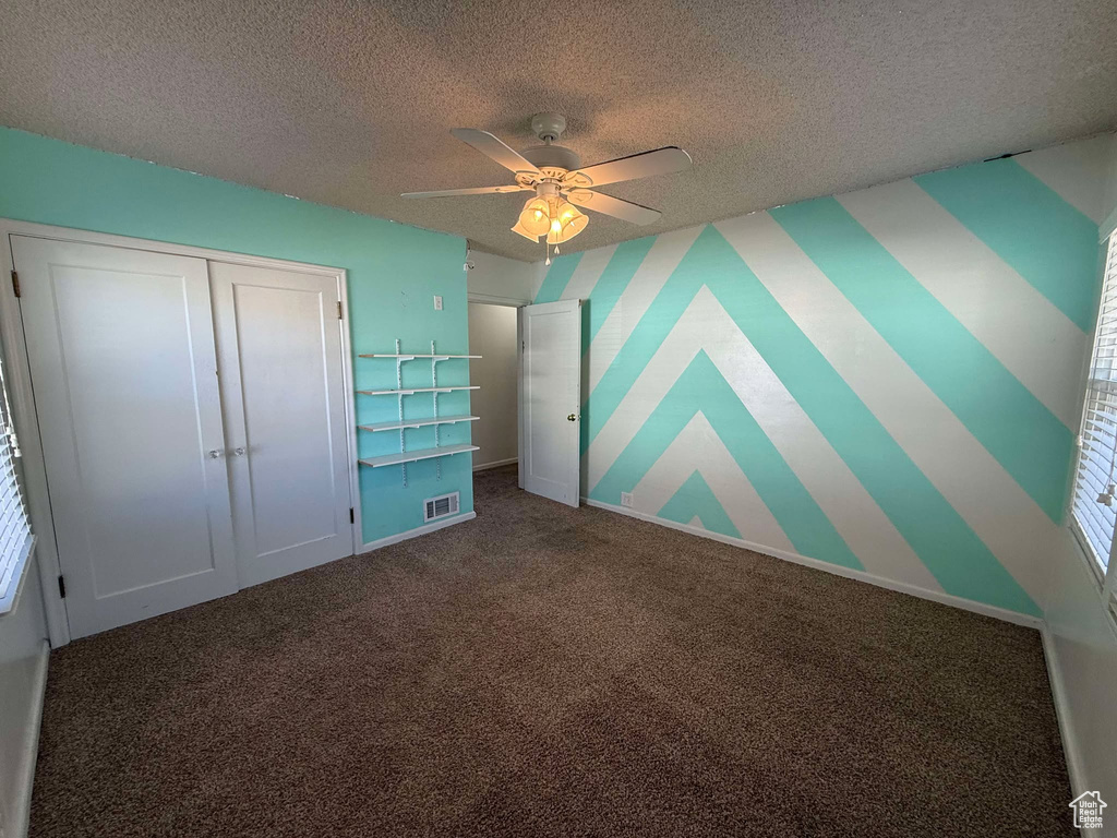 Unfurnished bedroom with ceiling fan, carpet flooring, a closet, and a textured ceiling