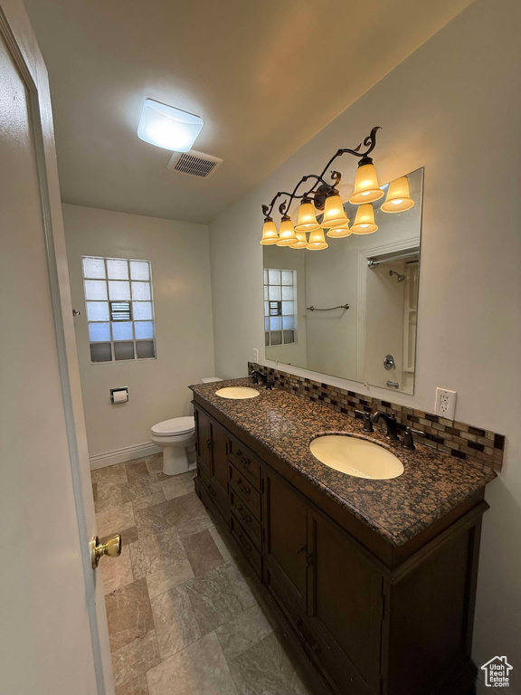 Bathroom featuring backsplash, vanity, toilet, and a wealth of natural light