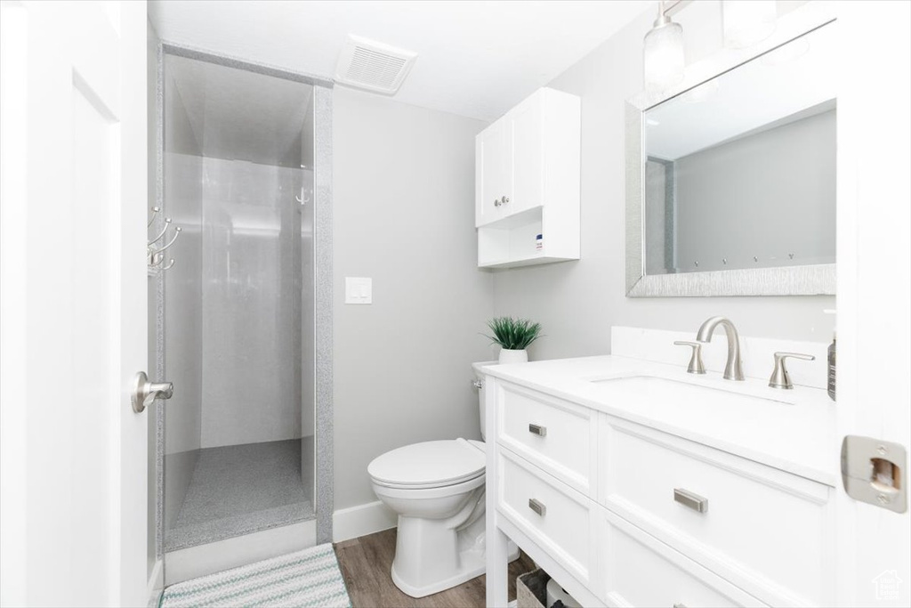 Bathroom featuring a shower, hardwood / wood-style floors, vanity, and toilet