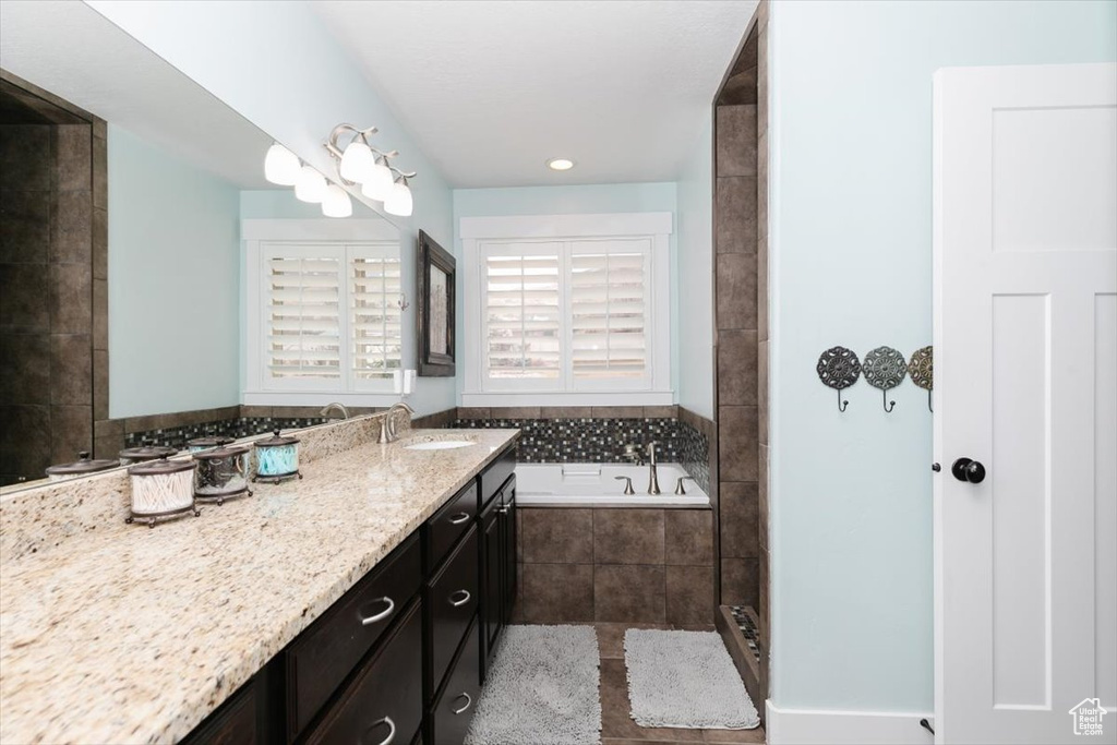 Bathroom with vanity and tiled tub