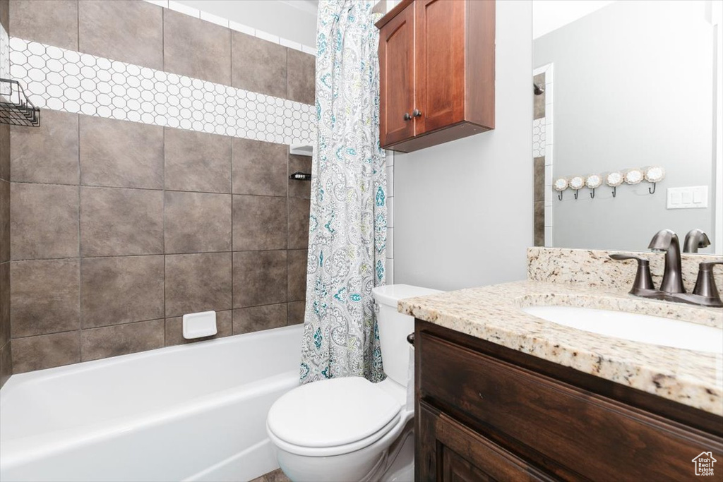 Full bathroom featuring shower / bath combination with curtain, vanity, and toilet