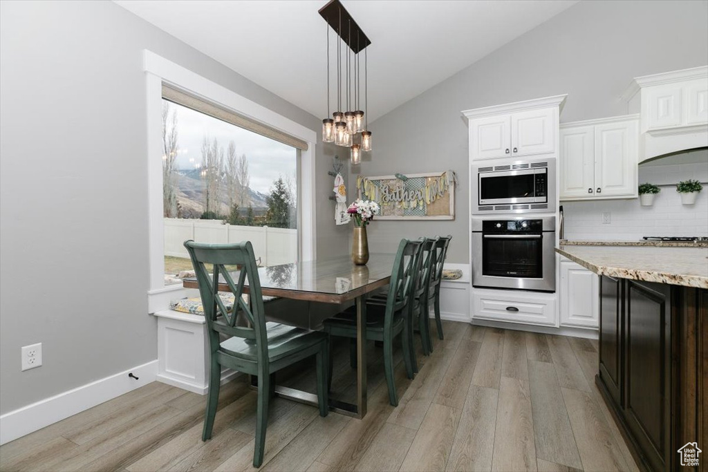 Dining area with lofted ceiling, a chandelier, and light wood-type flooring