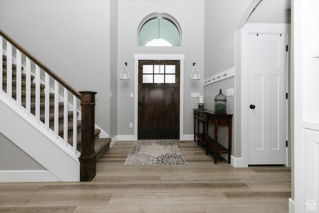 Foyer with light hardwood / wood-style floors and a high ceiling