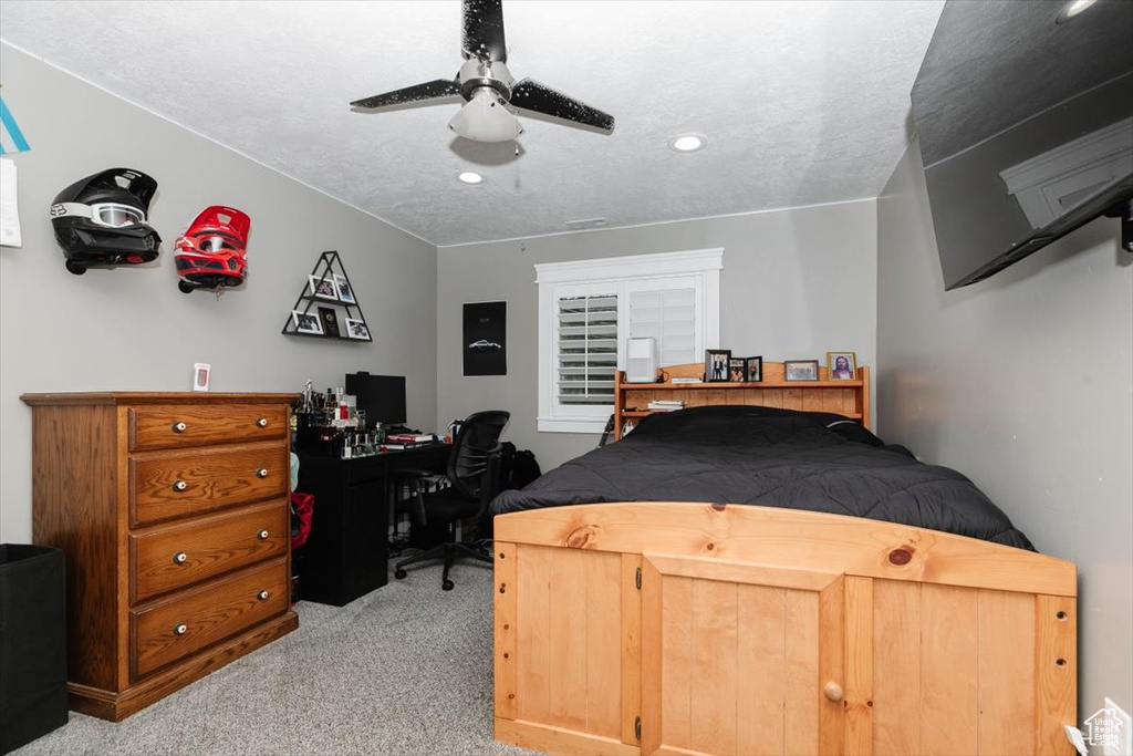 Carpeted bedroom featuring a textured ceiling and ceiling fan