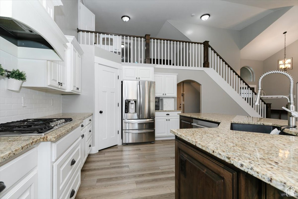 Kitchen featuring white cabinetry, stainless steel appliances, and hanging light fixtures