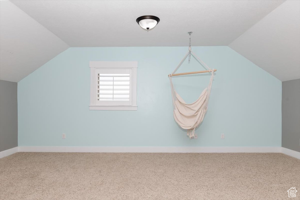 Additional living space featuring vaulted ceiling and carpet flooring