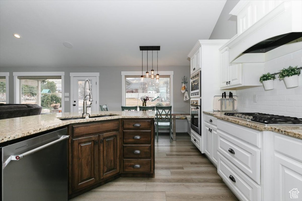 Kitchen with sink, dark brown cabinets, custom range hood, stainless steel appliances, and white cabinets