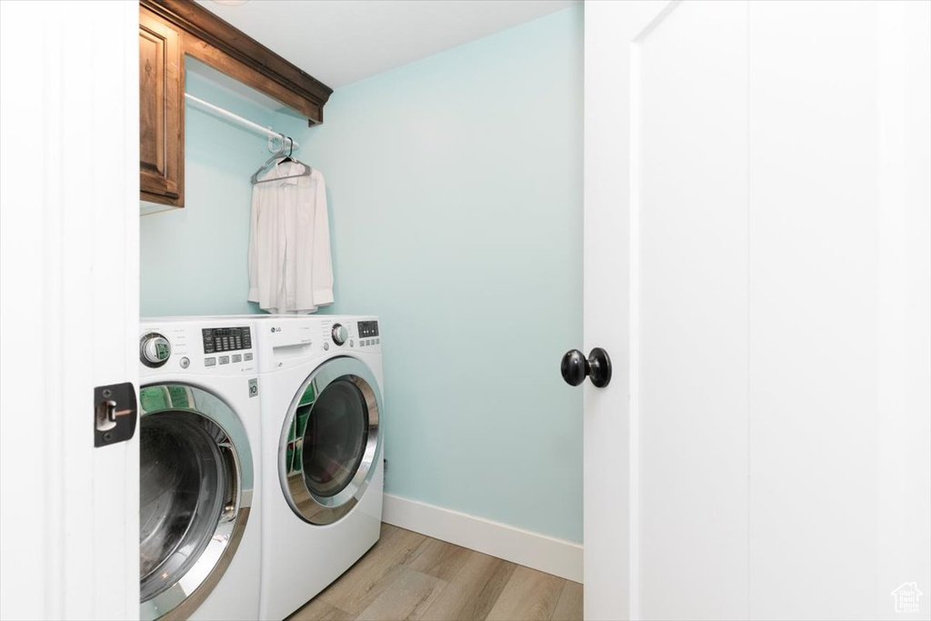 Clothes washing area featuring cabinets, light hardwood / wood-style floors, and washer and dryer