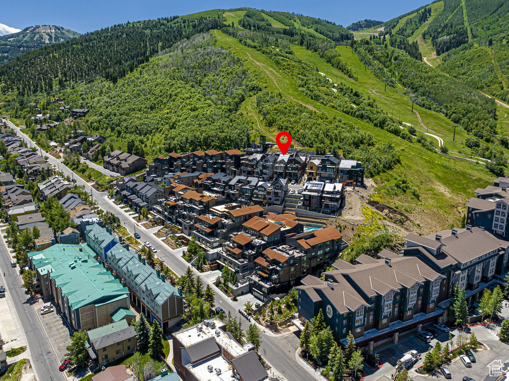 Aerial view of property's location featuring a mountainous background and a forest