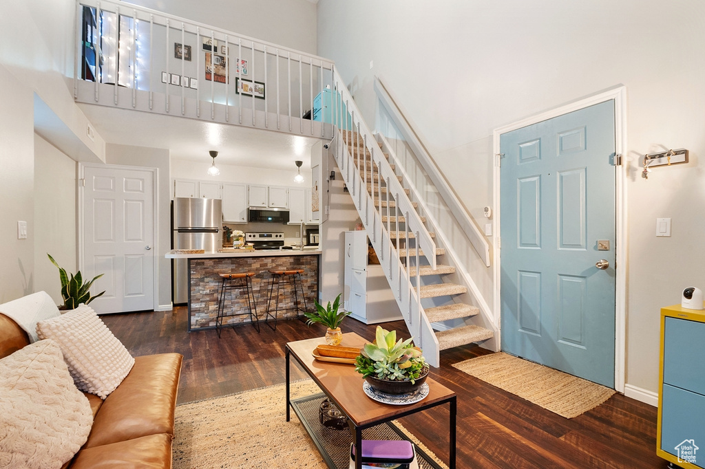 Living room with dark hardwood / wood-style flooring and a high ceiling