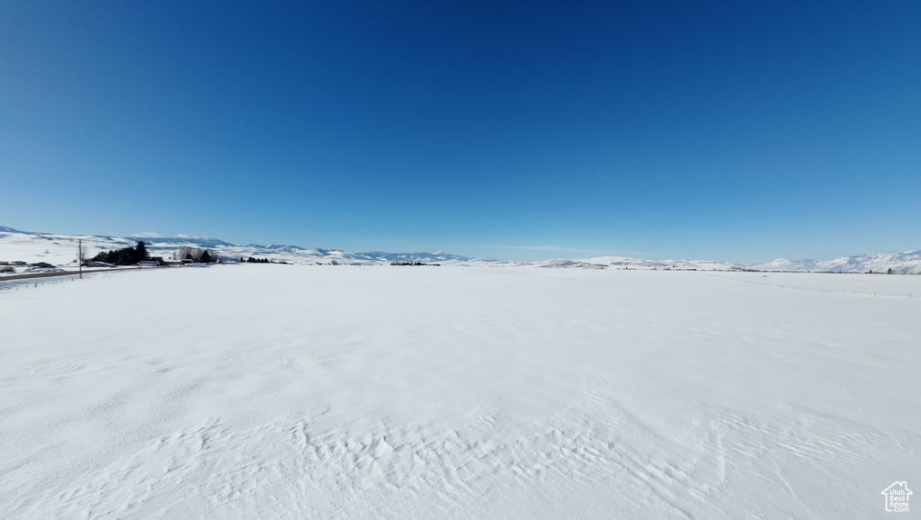 Yard covered in snow featuring a mountain view